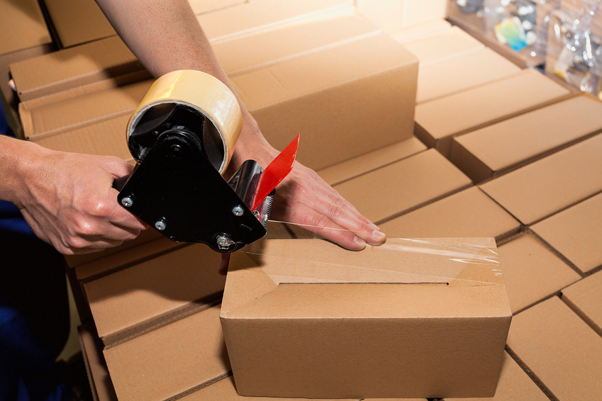 Worker using adhesive tape to close the boxes